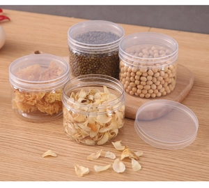 Detailed view of stackable clear food jars with screw lids on a wooden kitchen countertop