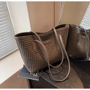Detail of dark brown woven leather tote bag texture and slim straps in natural light