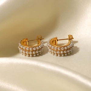 Detail of 18K gold plated C-shaped earrings featuring triple rows of white pearls
