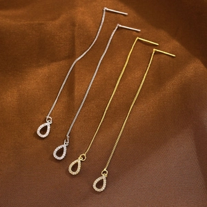 Detail of silver and gold drop earrings with zircon pavé on luxury brown silk