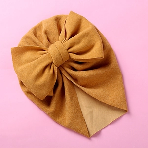 Detail view of ginger yellow baby turban hat with oversized bow in textured fleece fabric