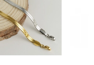 Macro detail of flat gold and silver stainless steel snake chains on wood base