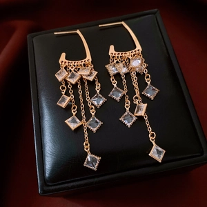 Close-up of 18K gold plated tassel earrings with cubic zirconia on black leather