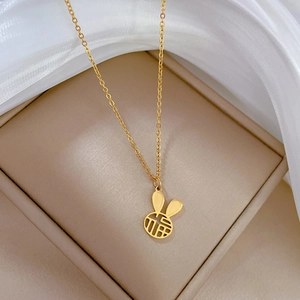 Detailed close-up of a golden rabbit pendant with Fu character on a cream display stand