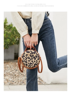 Detail of round leopard print crossbody bag with leather trim and gold metal logo