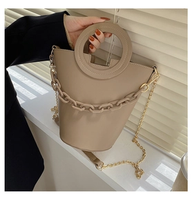 Close-up of khaki bucket bag featuring chunky acrylic chain and sleek round handle detail