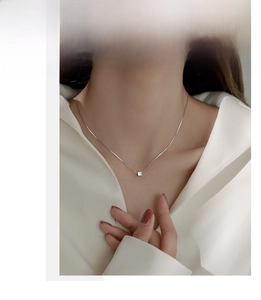 Detailed close-up of a minimalist S925 sterling silver square cube pendant necklace