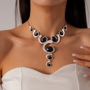 Detailed view of irregular silver necklace with a black oval stone on a model's neck