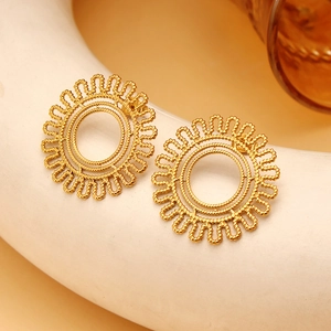 Golden hollow sunburst hoop earrings with radial texture on a white decorative dish