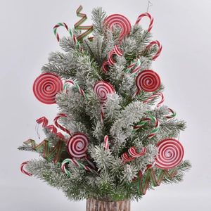 Mini snowy Christmas tree with red and white candy cane ornaments on wooden base