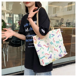 Detail of canvas tote bag featuring colorful geometric graffiti patterns and beige straps