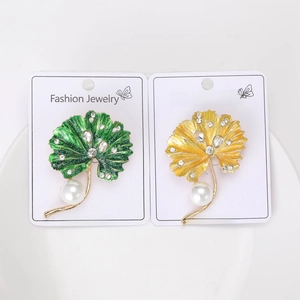 Detail of leaf-shaped enamel brooches with rhinestones and hanging pearls on cards