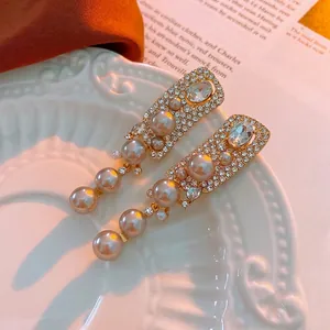 Orecchini vintage francesi con perle e nappe su un piatto decorativo bianco