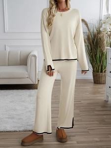 Detail of beige knit set featuring black contrast trim on sleeves and high-waist pants