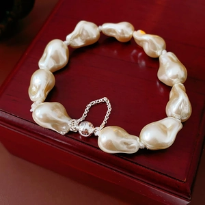 Macro shot of irregular baroque pearl bracelet with silver magnetic clasp on wooden box
