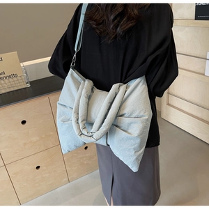 Detail of a large blue bow shoulder bag in nylon showing soft pleats and balletcore style