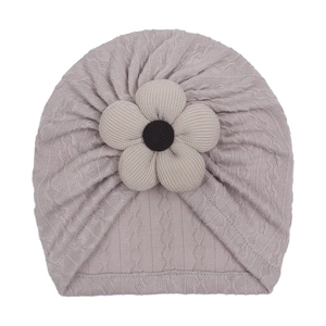 Detail of baby turban hat featuring purple cable knit texture and 3D floral accent