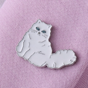 Detailed view of white enamel cat brooch pinned on pink knit fabric texture