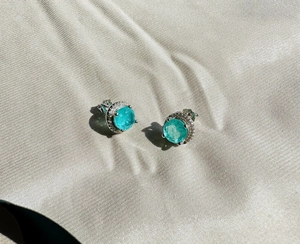 Macro shot of 8mm round Paraiba gemstone stud earrings with diamond halo on silk