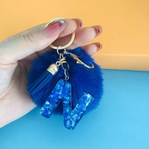Detail of blue pompom keychain with matching tassel and blue glitter resin letter N