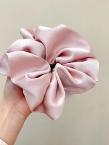 Detail of oversized light pink satin scrunchie showing silky texture and elegant folds