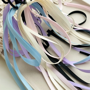 Detail of colorful satin ribbon bow hair ties in light blue and pink on a lace tray
