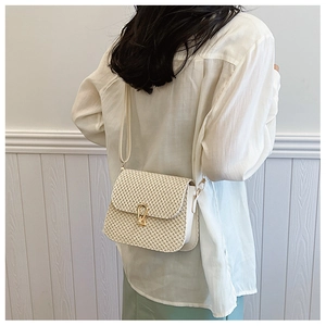 Detail of woven straw crossbody bag with golden horseshoe buckle and white leather side