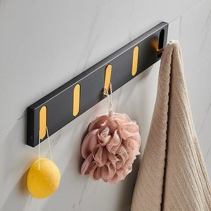 Wall-mounted matte black and gold folding hooks on marble wall with bath accessories