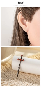 Détail macro de boucles d'oreilles épée noires avec zircons rouges au style punk