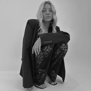 Dettaglio dei pantaloni in pizzo trasparente a vita alta con blazer nero abbinato