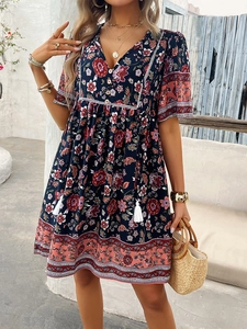 Detail of floral V-neck dress featuring bohemian print with buttons and tassel accents