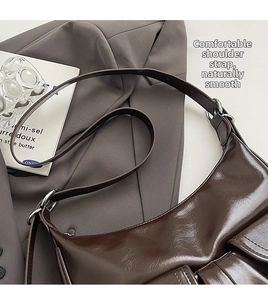 Detail of a dark brown hobo bag with glossy oil-wax texture and silver metal hardware