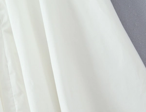 Macro shot of white halter dress fabric showing fine texture and smooth draping quality