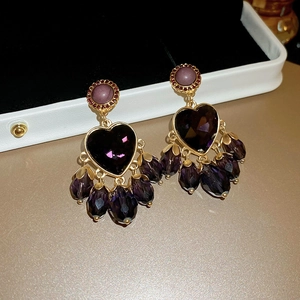Macro shot of vintage baroque earrings with purple heart gemstone and beaded tassels