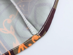 Macro view of dress hem stitching with ethnic pattern and vibrant orange thread detail