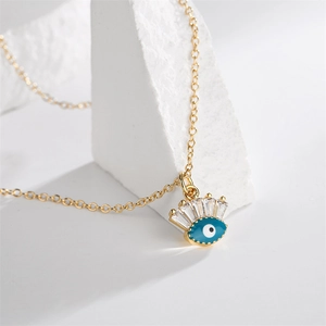 Detail of gold evil eye pendant necklace with blue enamel and rectangular zircon crystal