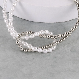 Macro shot of faux pearl and silver metal bead knotting detail on the crossover necklace