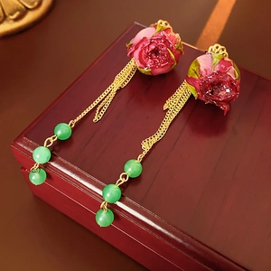 Vintage-Ohrringe mit roten Rosen, Goldketten und grünen Perlen auf einer Holzschachtel