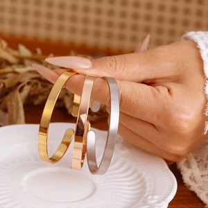 Close-up of minimalist C-shape stainless steel bracelets in gold, rose gold and silver
