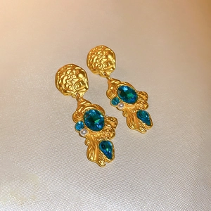 Detailed macro shot of vintage gold flower earrings with blue gems and pearl