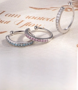 Dettaglio di ear cuff in argento con zirconi bianchi, rosa e blu su base di rame