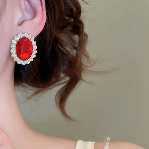 Close-up of vintage oval red gemstone earrings with sparkling crystal halo for women
