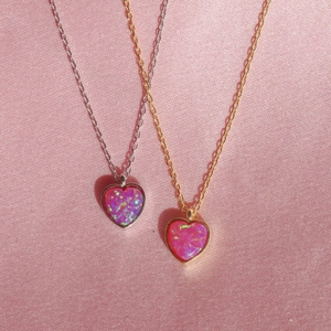 Pink heart opal necklaces in gold and silver finishes on elegant pink satin fabric