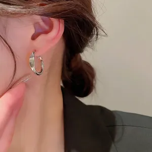 Minimalist silver twist hoop earrings shown on model for size and style perspective
