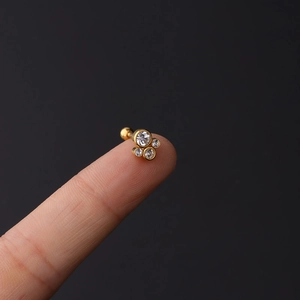 Macro shot of gold stainless steel stud featuring four clear zircon stones on a fingertip
