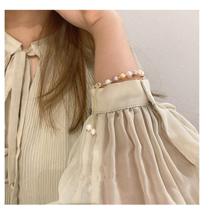 Detail of multi-color freshwater pearl bracelet with golden sunflower tassel charm