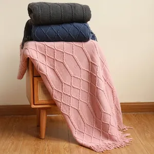 Detail of cable knit throw blankets with fringe in pink, dark blue and dark grey