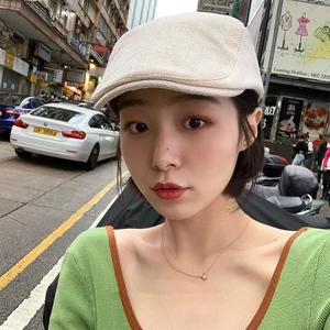 Close-up of knit texture on cream white newsboy cap worn by a model in a city street