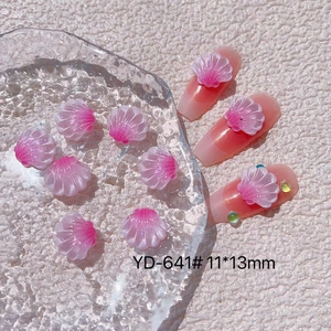 Detailed view of pink shell nail charms with shimmer on gradient manicured nails