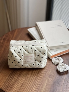 Detailed shot of quilted corduroy mini bag with black heart patterns and French label
